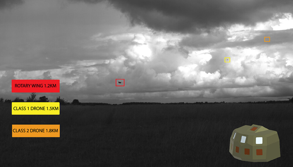 Rheinmetall's Skyblazer in a live trial: black and white image of a landscape with clouds above. 3 coloured boxes highlighting regions of interest and classifications of a rotary wing and 2 drones at different distances.