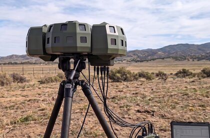 Rheinmetalls Skyblazer Weitbereichssensor auf einem Tripod – Beispielbild des Skyblazer in 360°-Ansicht auf KI-generiertem Hintergrund